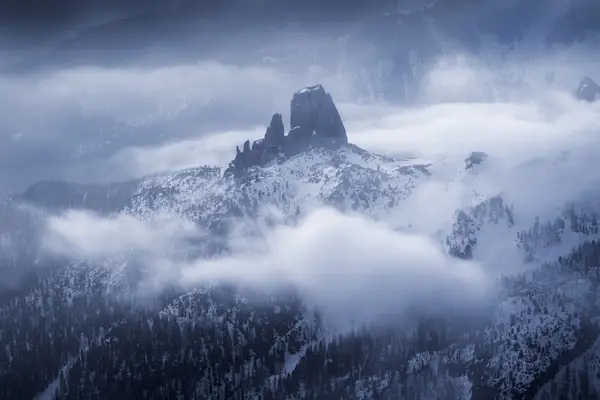 Cinque Torri peaks emerging through winter clouds and snowfall in the Dolomites