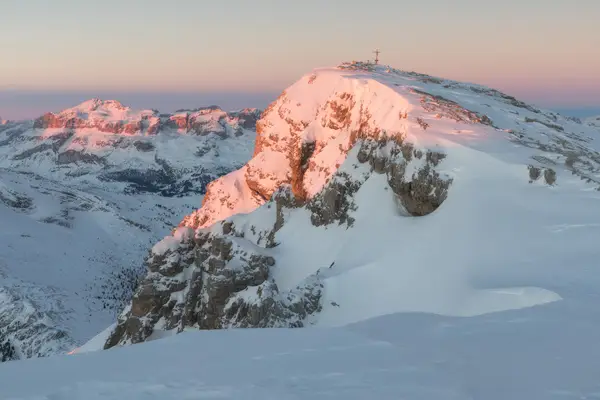 Snow-covered summit ridge of Lagazuoi illuminated by sunrise in the Dolomites
